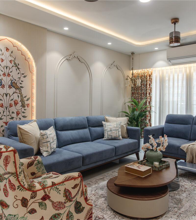 Living room with peacock mural and blue sofas by SpazioLiv